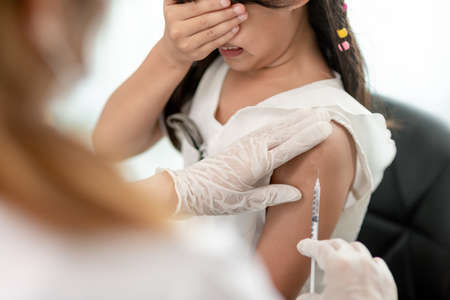 Vaccination concept. Female doctor vaccinating cute little girl in clinic