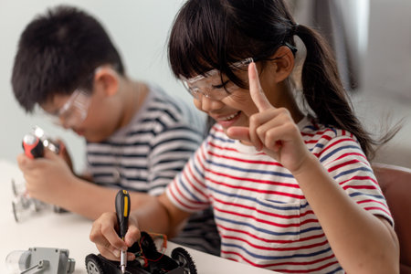 two Asian children having fun learning coding together, learning remotely at home, STEM science, homeschooling education, fun social distancing, isolation, new normal conceptの写真素材