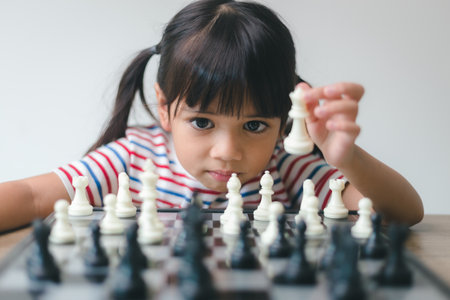 Asian little girl playing chess at home.a game of chessの写真素材