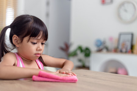 happy little Asian girl learning to clean with a rag in the living room at home. housework and household concept.の写真素材