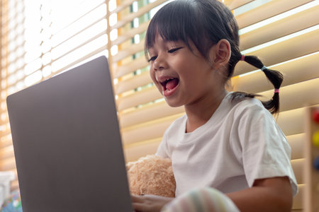 Asian girl using Laptop computer for online study homeschooling during home quarantine. homeschooling, online study, home quarantine, online learning, corona virus or education technology conceptの写真素材