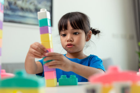 Adorable little girl playing toy blocks in a bright room