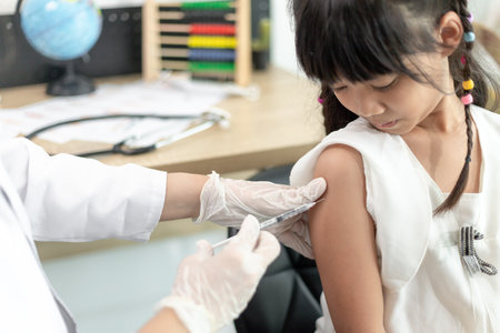 Vaccination concept. Female doctor vaccinating cute little girl in clinicの写真素材