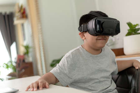 Asian Little boy with VR glasses studying sciences at home,curious student wears a virtual reality...