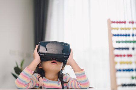 Child with virtual reality headset sitting behind table indoors at homeの写真素材