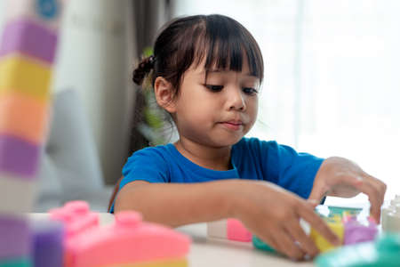 Adorable little girl playing toy blocks in a bright roomの写真素材