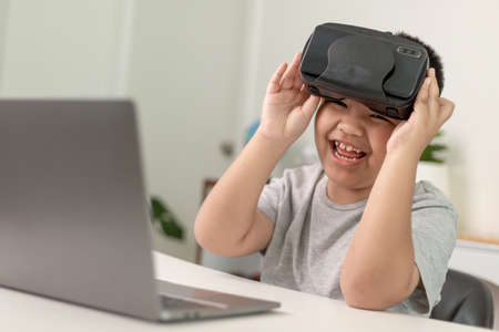 Asian Little boy with VR glasses studying sciences at home,curious student wears a virtual reality headset to study science home online study futuristic lifestyle learningの写真素材