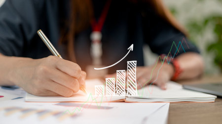 Businesswoman draws an increasing trend arrow and a rising chart from plan to goal. It is a...