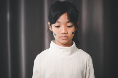 A child with the flag of Ukraine is crying. Sadness longing hope. Children's tears from the war. Evacuation of civilians. Freedom to Ukraineの写真素材
