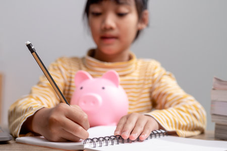 Asian little girl wearing a graduation cap with a pink piggy bank, Saving money, investment the future,の写真素材