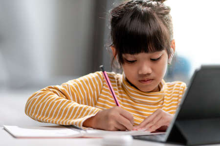 Asian girl students in online learning classes study online with Tablet at home.