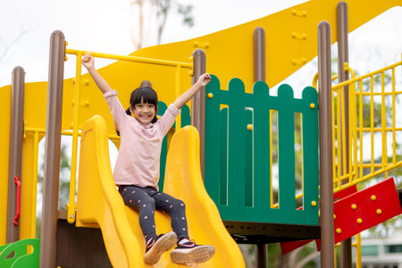 Child playing on outdoor playground. Kids play on school or kindergarten yard. Active kid on colorful slide and swing. Healthy summer activity for children. Little boy climbing outdoors.の写真素材