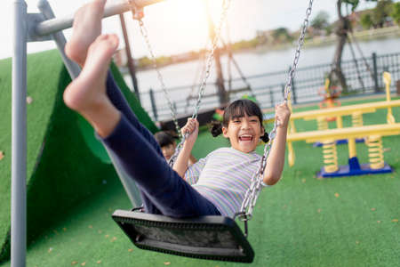A little girl is having fun riding a swing.の写真素材