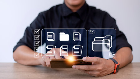 Document Management System (DMS) being setup by IT consultant working on laptop computer in office. Software for archiving, searching and managing corporate files and informationの写真素材