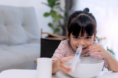Little asian girl saline nasal wash nose at home.の写真素材