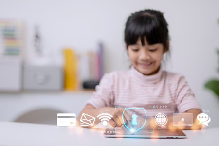 Child safety online. Little girl using tablet at home. icon of internet blocking app on foregroundの写真素材