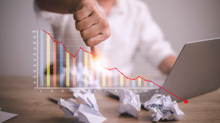 Depressed Businessman Leaning His Head Below a Bad Stock Market Chartの写真素材