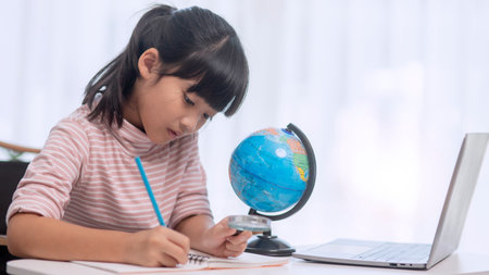 Asian little girl is learning the globe model, concept of save the world and learn through play activity for kid education at home.の写真素材