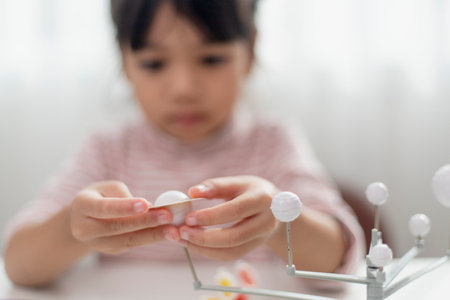 Asian Little girl studies the solar system in geography class. looking at the scale model of planetsの写真素材