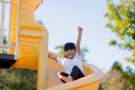 Child playing on outdoor playground. Kids play on school or kindergarten yard. Active kid on colorful slide and swing. Healthy summer activity for children. Little girls climbing outdoors.の写真素材