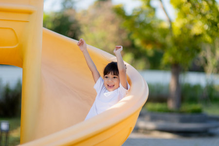Child playing on outdoor playground. Kids play on school or kindergarten yard. Active kid on colorful slide and swing. Healthy summer activity for children. Little girls climbing outdoors.の写真素材