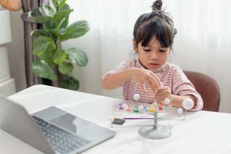 Asian Little girl studies the solar system in geography class. looking at the scale model of planetsの写真素材