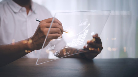 Businessman draws an increasing trend arrow and a rising chart from plan to goal. It is a representation of the idea of corporate investment development.の写真素材