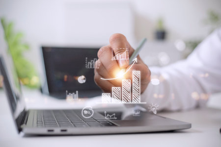 Businessman draws an increasing trend arrow and a rising chart from plan to goal. It is a...