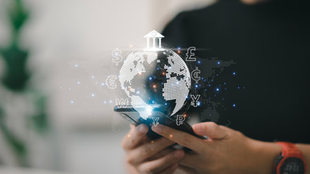 Women use mobile phones and laptop computers for money transfers and currency exchanges between...