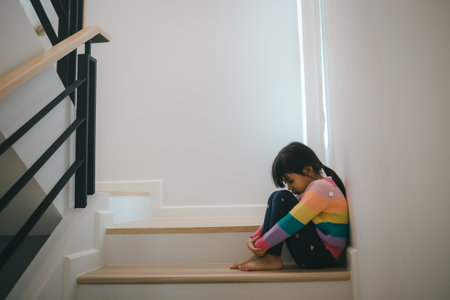 Sad child from this father and mother arguing, family negative concept. little girls sitting and crying at the stairs.の写真素材