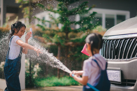 Sibling Asian girls wash their cars and have fun playing indoors on a hot summer day.の写真素材