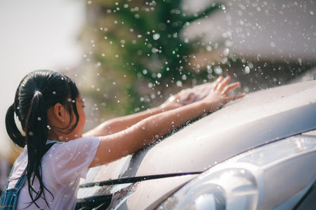 Sibling Asian girls wash their cars and have fun playing indoors on a hot summer day.の写真素材