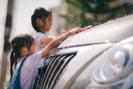 Sibling Asian girls wash their cars and have fun playing indoors on a hot summer day.の写真素材