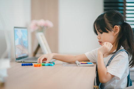 Cute little Asian girl enjoying while playing with toys or blocks, sitting at the table.の写真素材