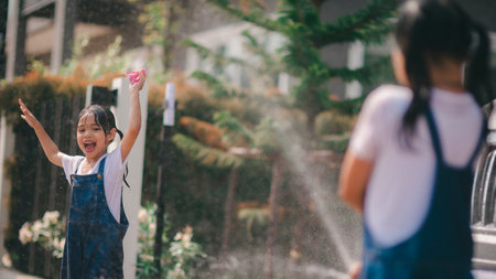 Sibling Asian girls wash their cars and have fun playing indoors on a hot summer day.の写真素材