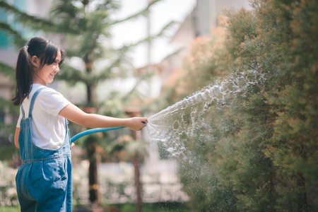 Asian little child girl water the plants. kid helps to care for the plants in the garden.の写真素材