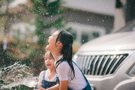 Sibling Asian girls wash their cars and have fun playing indoors on a hot summer day.の写真素材