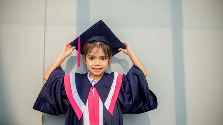 Happy Asian girls in graduation gowns on their graduation day at school.Graduation concept with copy space.の写真素材