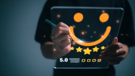 The customer creates a happy face smiling symbol using a digital pen on a futuristic virtual interface screen. The consumer answered the survey in a conceptual way.の写真素材