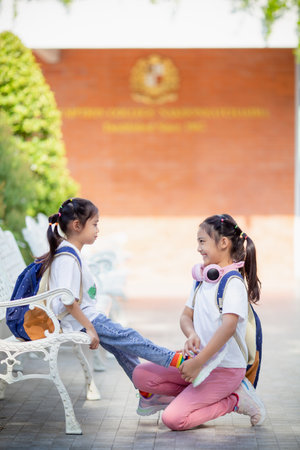 Back to school. Cute little girl kindness ties shoelaces for a friend.の写真素材
