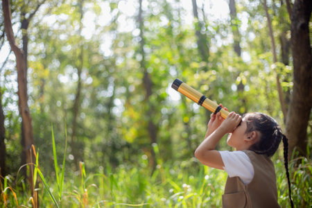 Happy Little Asian girls looking ahead and smiling child with the binoculars in the park. Travel and adventure concept. Freedom, vacationの写真素材