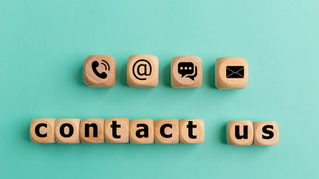 Contact us text on wooden cubes on a blue background. Wooden cube symbol telephone, mail, address,...