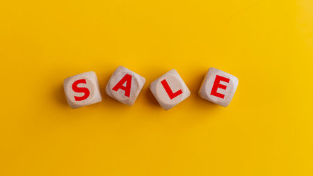 Word SALE on wooden cubes on yellow background. Top view. Price discount, promotion announcement, and shopping concept.の写真素材