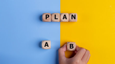 The hand of a businessman choosing business plan B out of two options on a yellow and blue background. Business strategy and decisions concept.の写真素材