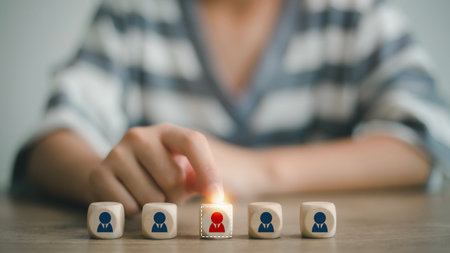 The woman picks a red human icon on the wooden cube. Customer rating employees by service experience, Human Resources management chooses a leader for the team resources management and recruitment.の写真素材