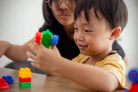 Asian cute brother and sister play with a toy block designer on the table in the living room at home. Concept of siblings bonding, friendship, and learning through play activity for kid development.の写真素材