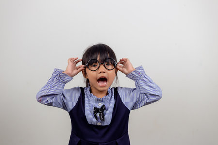 cute little preschooler girl isolated on grey studio background wear glasses look at camera, small...