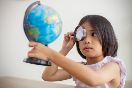Asian little girl is learning the globe model, concept of save the world and learn through play activity for kid education at home.の写真素材