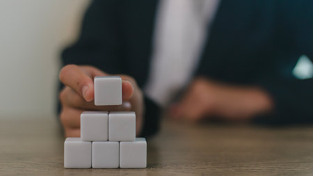 Businesswomen stack blank wooden cubes on the table with copy space, empty wooden cubes for input wording, and an infographic iconの写真素材
