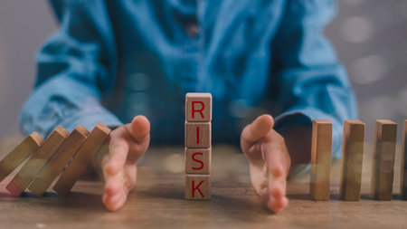 Hand of a businessman who is stopping or preventing a falling block.Risk protection concept,...